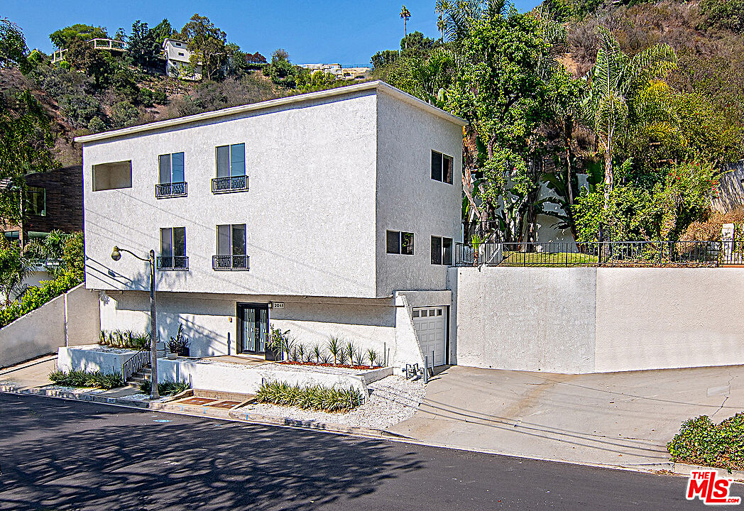 2041 Roscomare Road Los Angeles, CA 90077 - Photo 27 of 28 a view of a white house with a yard and sitting area