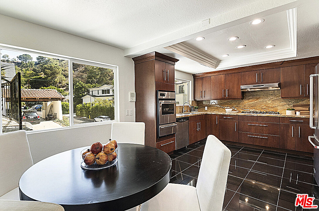 2041 Roscomare Road Los Angeles, CA 90077 - Photo 9 of 28 a kitchen with stainless steel appliances granite countertop a stove a refrigerator a kitchen island a dining table and chairs