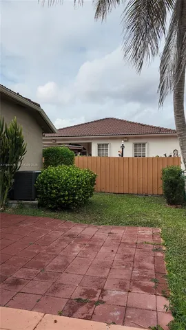 a view of a backyard with potted plants and large tree
