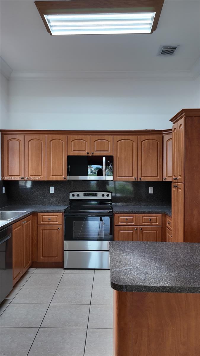 3265 Southwest 153rd Place Miami, FL 33185 - Photo 9 of 39 a kitchen with stainless steel appliances granite countertop a stove a sink and a microwave