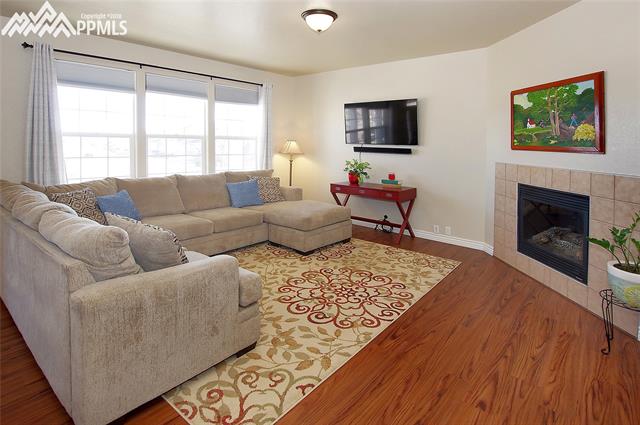 9352 St.George Road Peyton, CO 80831 - Photo 3 of 25 Bright living room with gas fireplace and wood laminate flooring