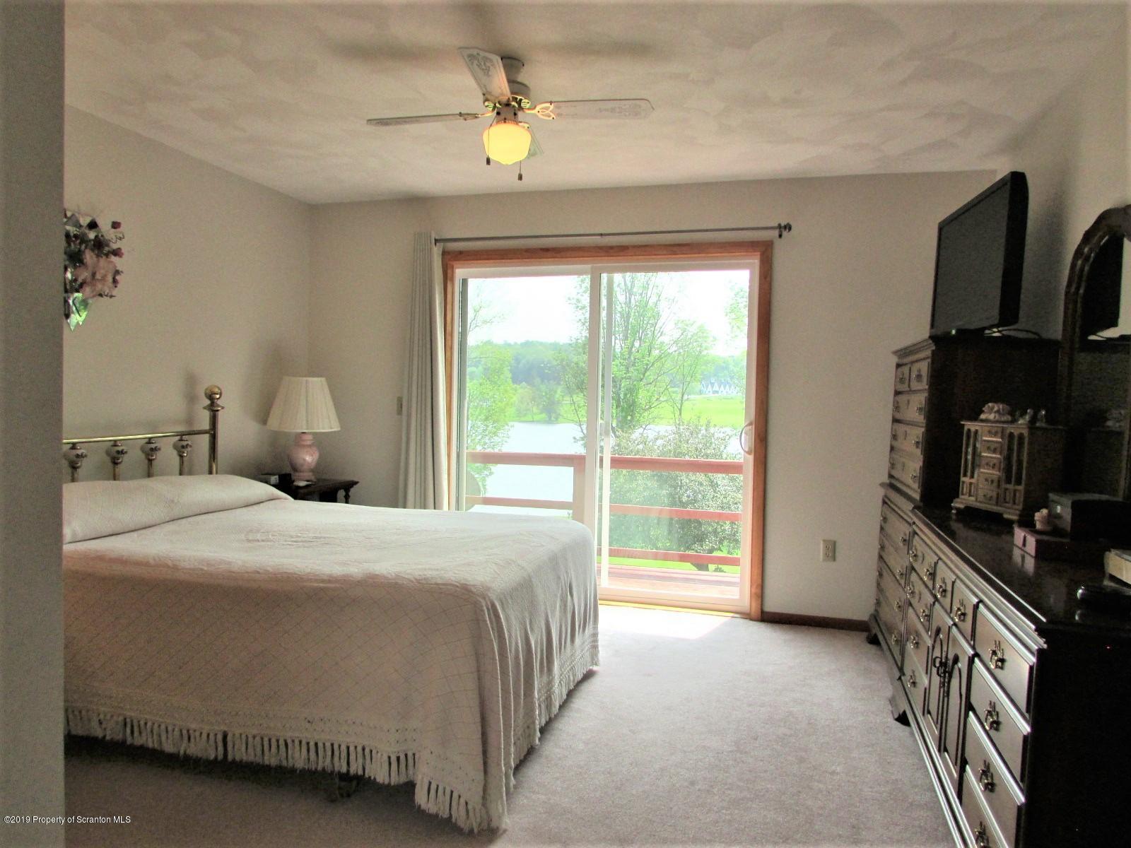 1315 Old County Road Montrose, PA 18801 - Photo 40 of 74 a bedroom with a bed a flat screen tv and chandelier