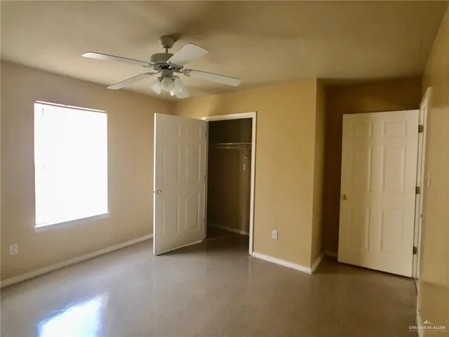 an empty room with a window and a ceiling fan