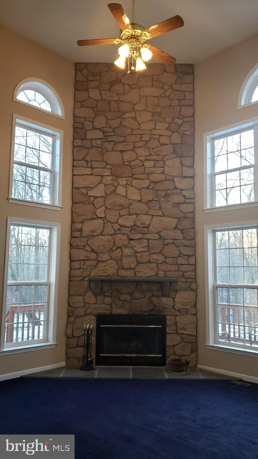 8637 Willow Run Road Baltimore, MD 21244 - Photo 17 of 56 a living room with a fireplace a chandelier and windows