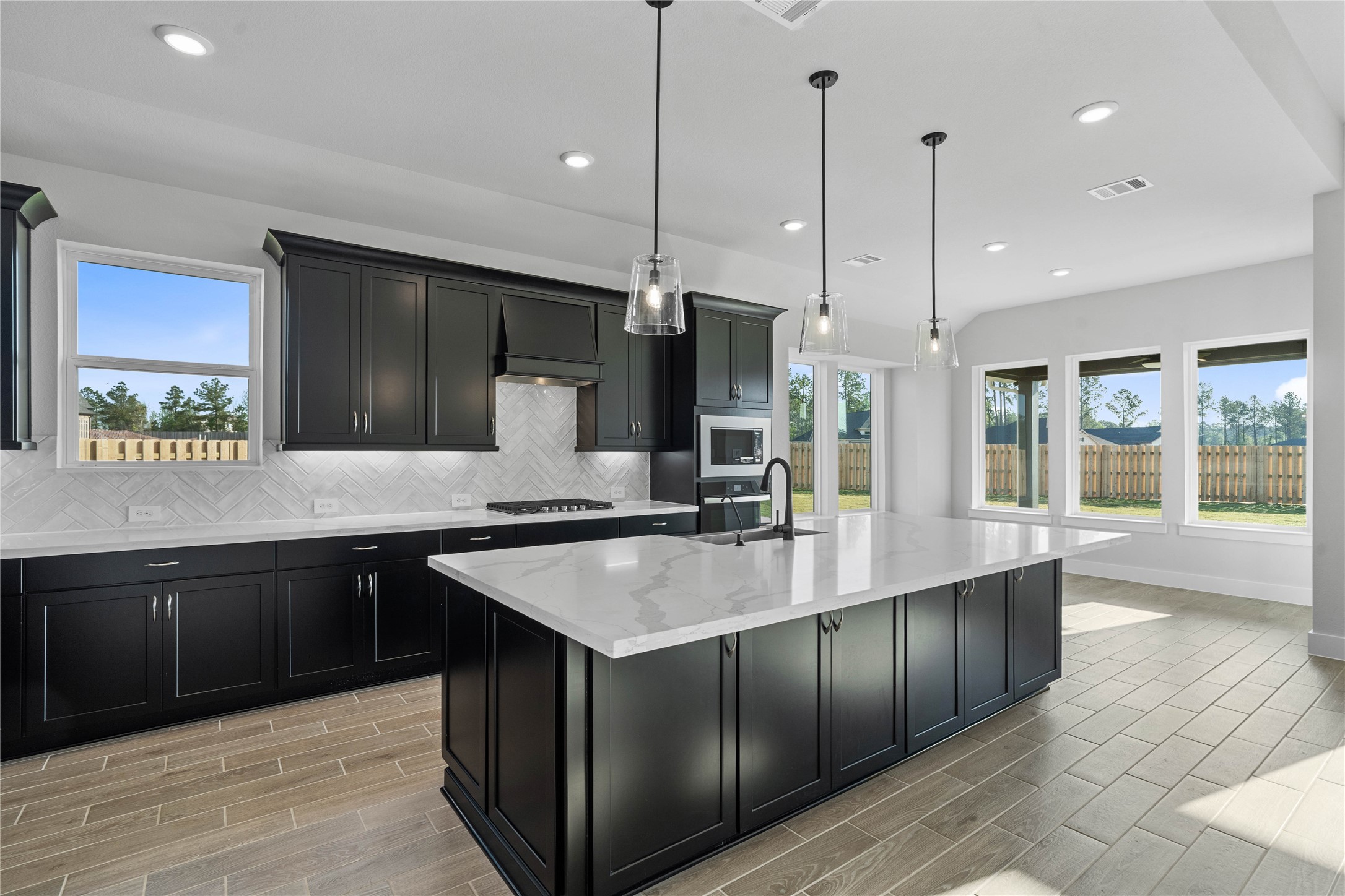2114 Rowl Street Montgomery, TX 77316 - Photo 23 of 50 This light-filled kitchen balances sleek modernity with warm accents, creating a perfect hub for daily living and entertaining. The expansive island offers ample prep and dining space, complemented by a seamless wall of integrated cabinetry and high-end built-in appliances.