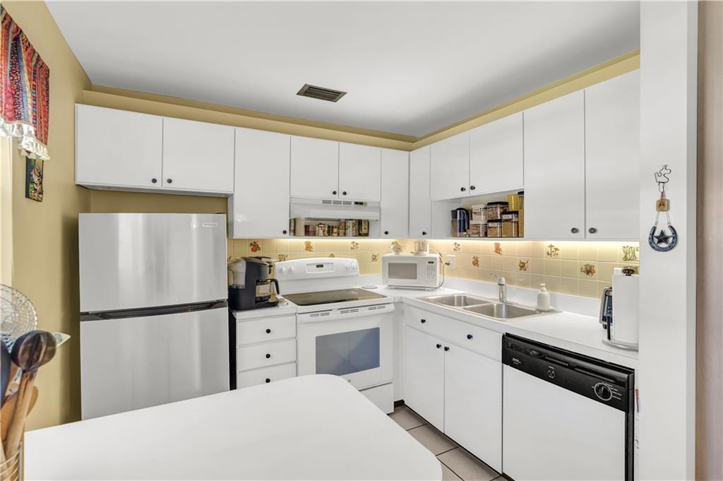 35 Pine Arbor Lane, Unit 202 Vero Beach, FL 32962 - Photo 2 of 16 a kitchen with white cabinets and white appliances