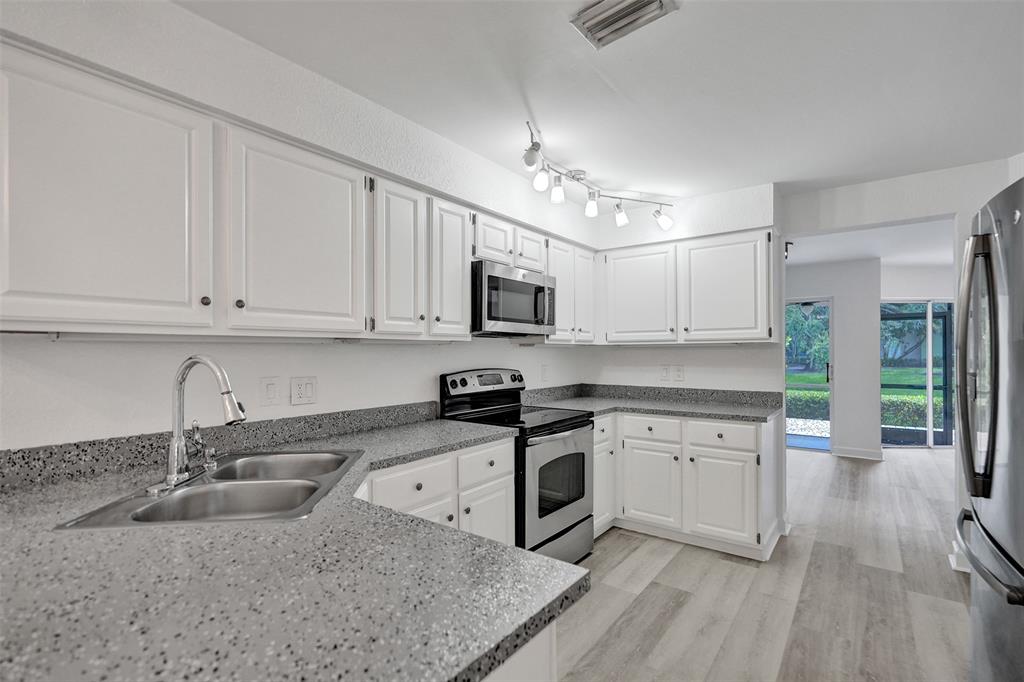 11652 Northwest 19th Drive Coral Springs, FL 33071 - Photo 15 of 52 a kitchen with stainless steel appliances granite countertop a sink dishwasher a stove and a microwave oven with white cabinets