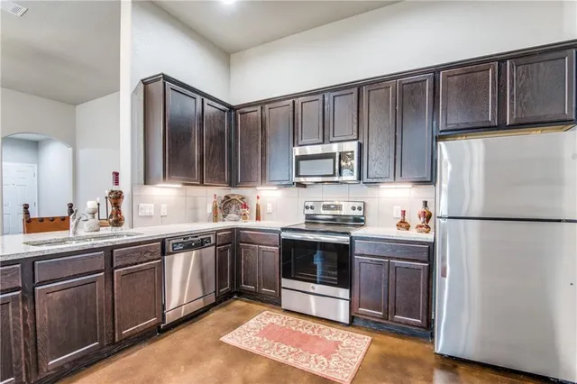 a kitchen with stainless steel appliances granite countertop a refrigerator stove a sink and dishwasher with wooden floor