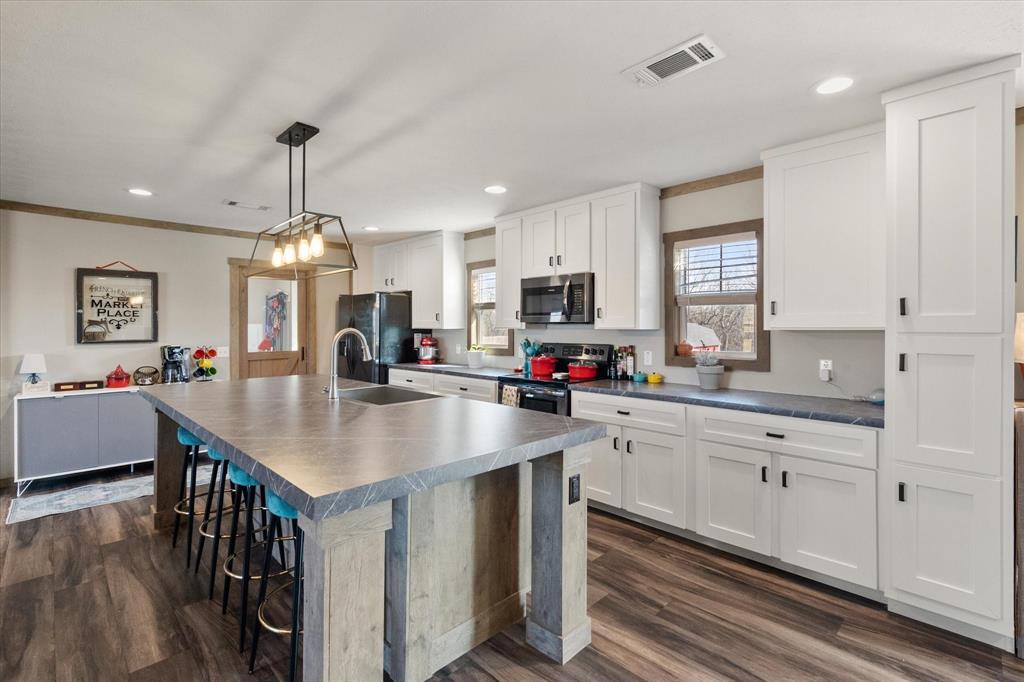 216 Southeast County Road Corsicana, TX 75109 - Photo 7 of 37 a kitchen with kitchen island granite countertop a sink cabinets and wooden floor