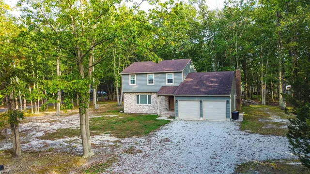 a front view of a house with a garden and tree