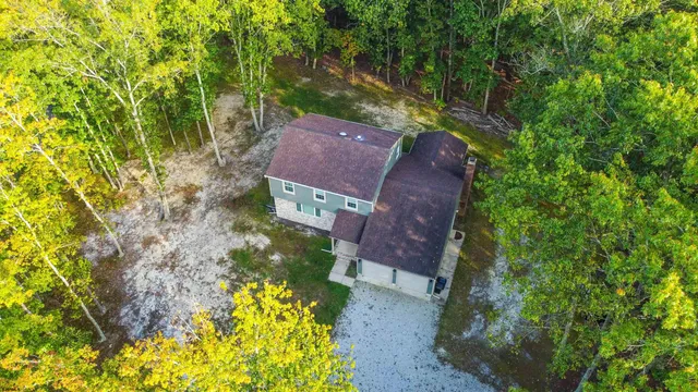 an aerial view of a house with a yard and large trees