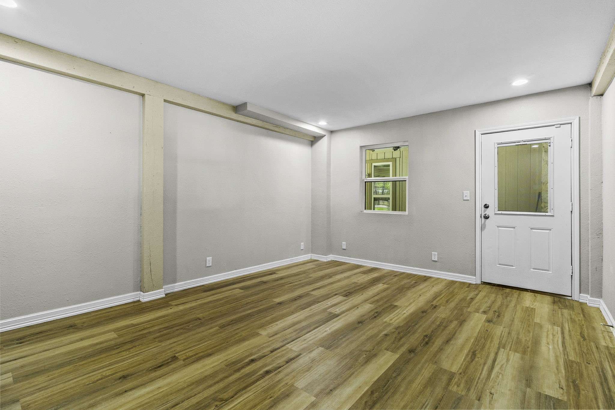 21 Red Oak Circle Point Blank, TX 77364 - Photo 21 of 32 This room features a clean, modern design with light wood flooring, neutral walls, recessed lighting, and a white door with a window, offering a bright and inviting space.
