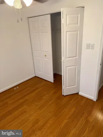 a view of an empty room with wooden floor and closet