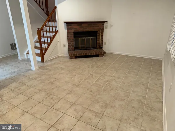 a view of an empty room with wooden floor and fireplace
