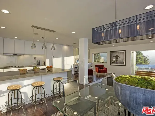 a kitchen with stainless steel appliances granite countertop a stove a sink a dining table and chairs with wooden floor
