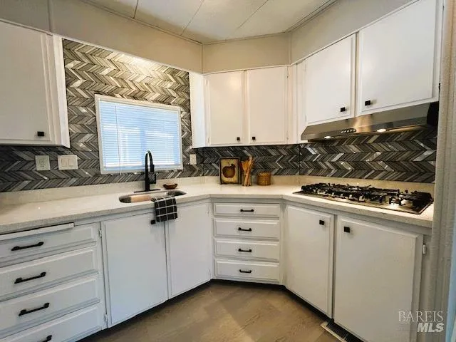 a kitchen with white cabinets and sink