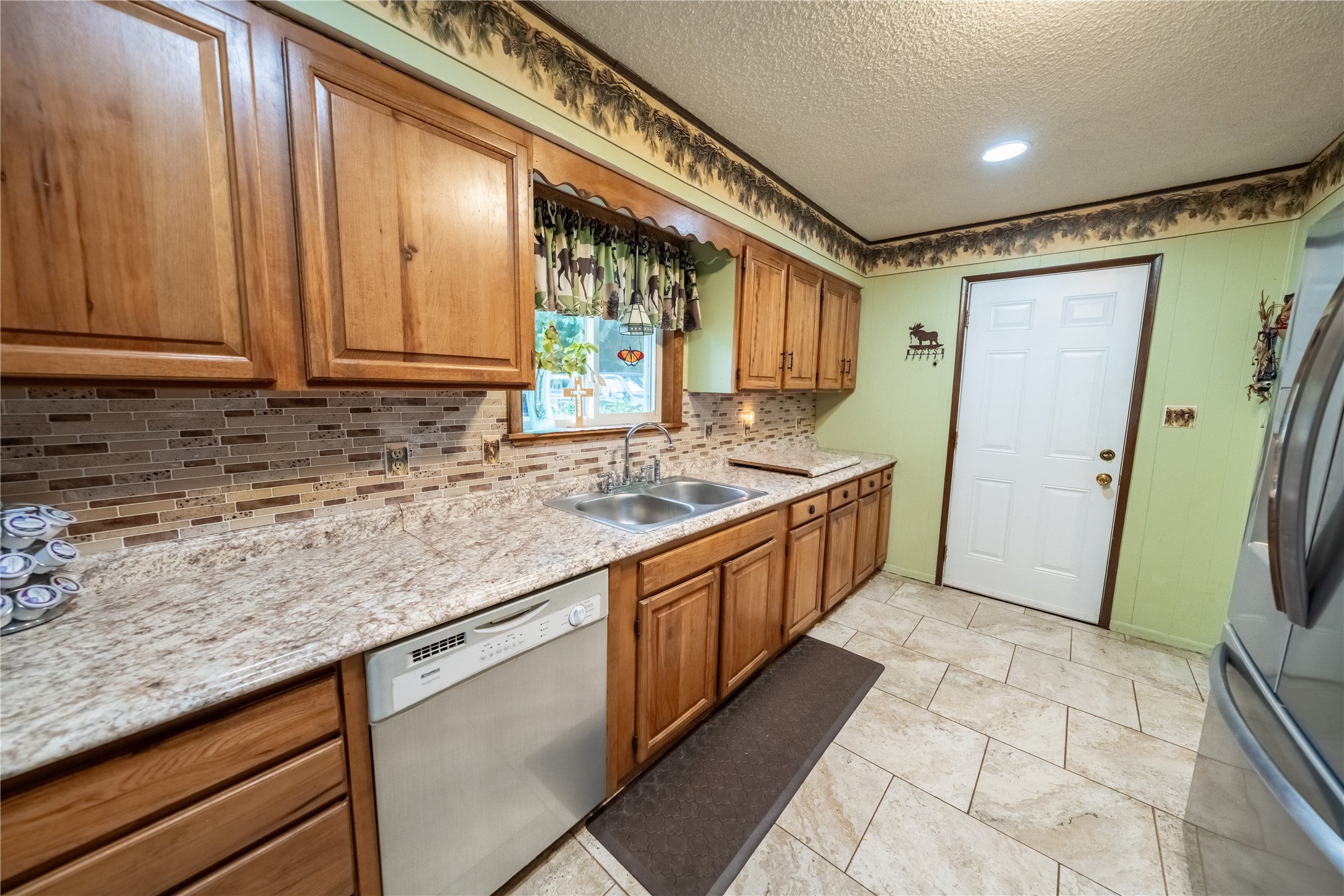 644 Waterfront Road Troy, MT 59935 - Photo 48 of 66 Kitchen featuring brown cabinetry, stainless steel appliances, a textured ceiling, backsplash, and light stone countertops