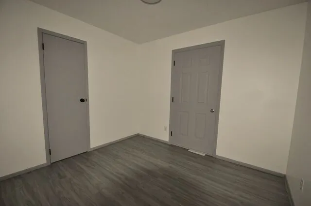 a view of an empty room with wooden floor and closet