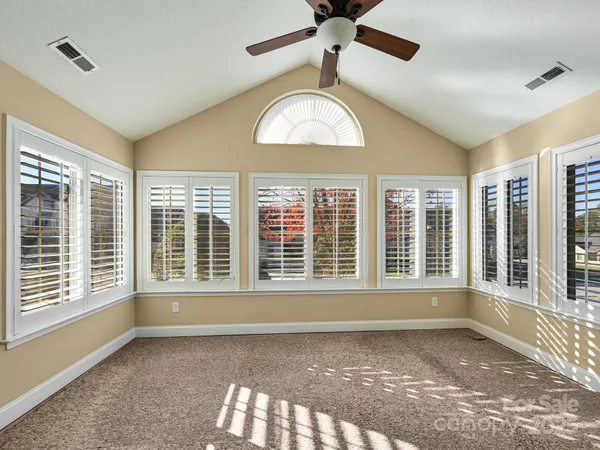 a view of an empty room with a window and a kitchen