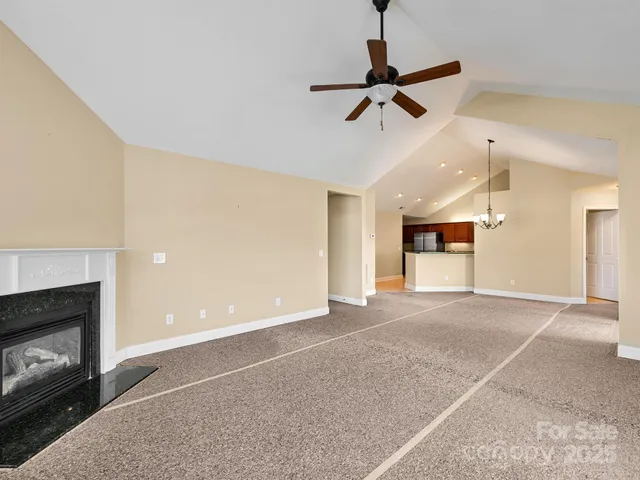 a view of empty room with a fireplace and a ceiling fan