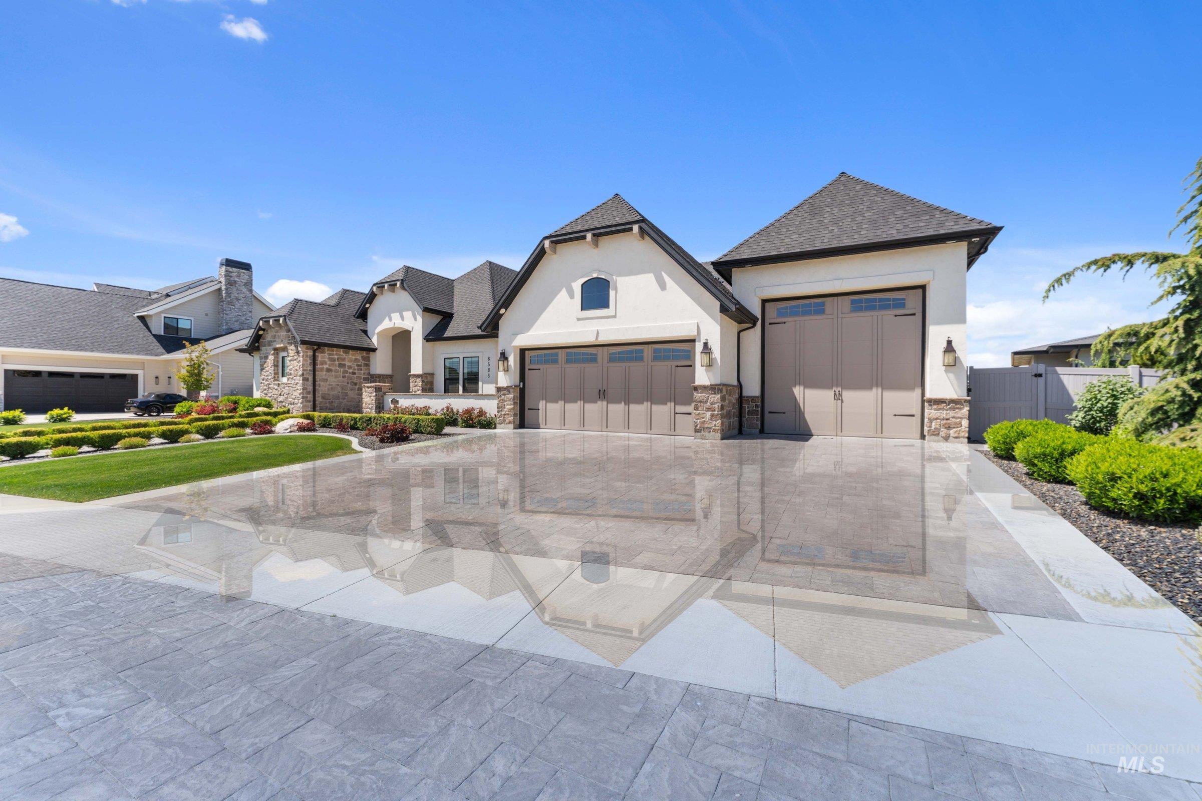 6585 South Pemberley Way Meridian, ID 83642 - Photo 1 of 43 Stucco and stone facade home featuring multiple garage bays with carriage-style doors, a gabled entry, and a stamped concrete driveway