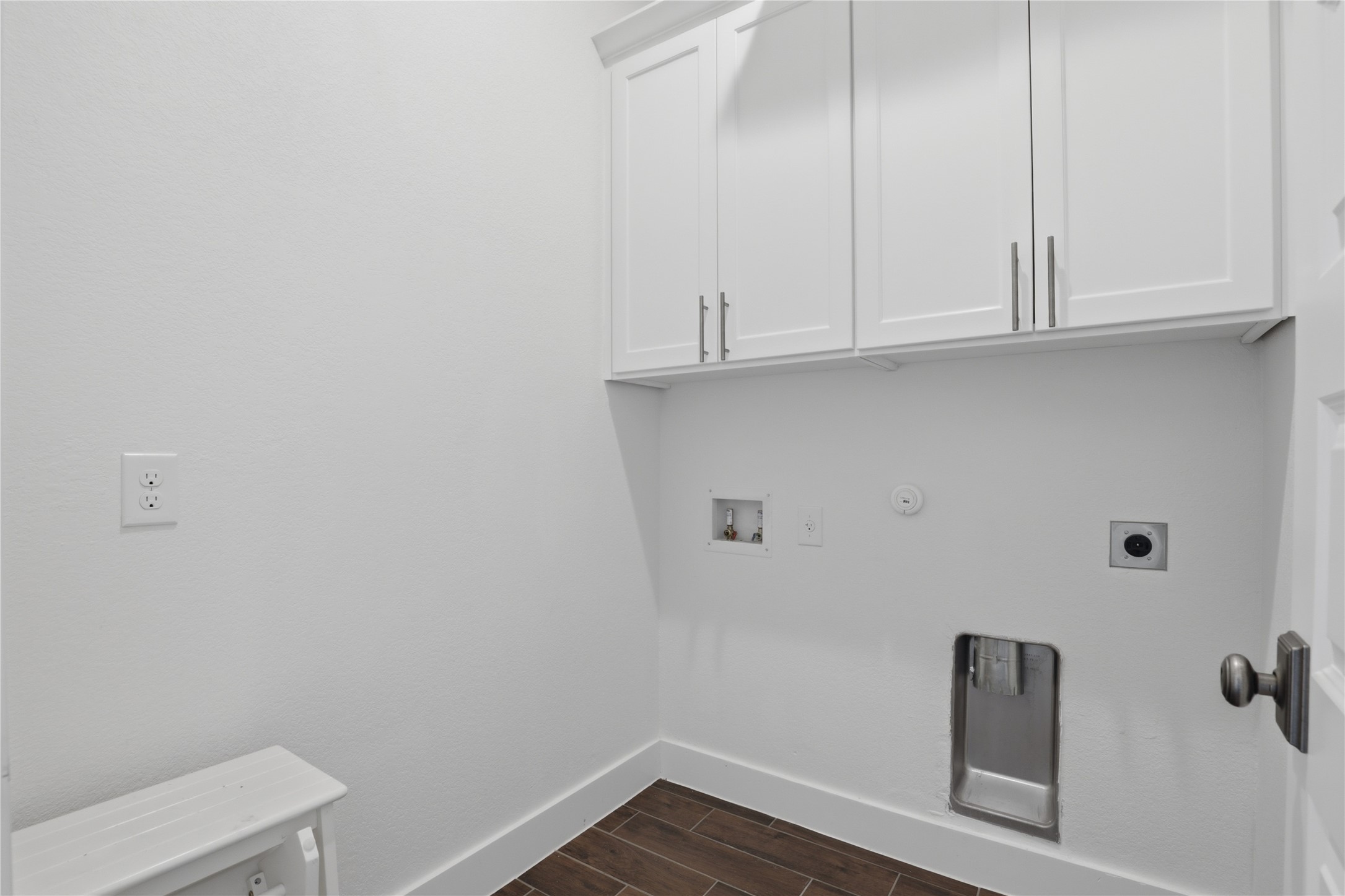 133 Greg Lane Jarrell, TX 76537 - Photo 21 of 24 Dedicated utility room featuring overhead white cabinetry with brushed nickel hardware, wood-finish flooring, and white baseboards