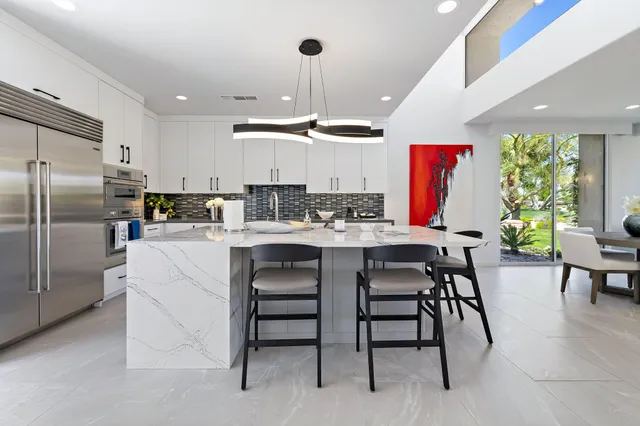 a kitchen with stainless steel appliances kitchen island granite countertop a table chairs and a refrigerator