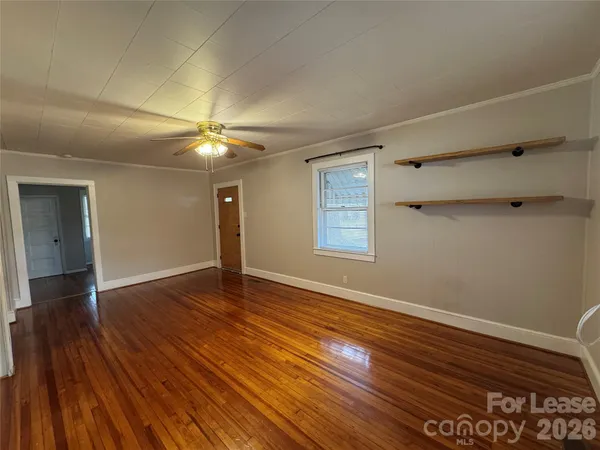a view of an empty room with wooden floor and a window