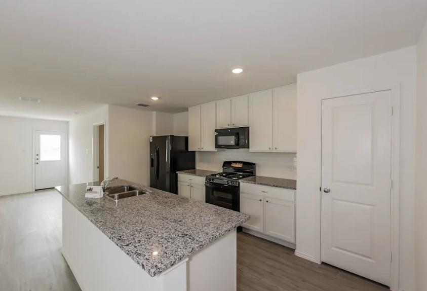 10225 Hackberry Spg Way Crowley, TX 76036 - Photo 6 of 11 Kitchen featuring black appliances, light stone countertops, dark wood-style floors, white cabinetry, and recessed lighting