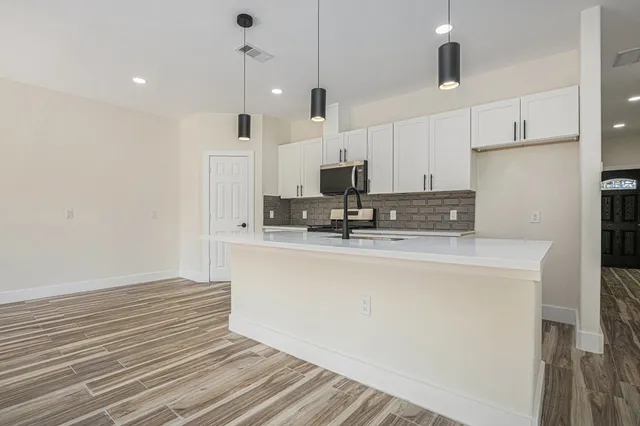 a kitchen with kitchen island a sink stainless steel appliances and white cabinets