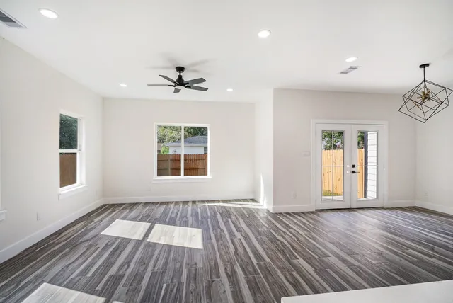 an empty room with wooden floor and windows