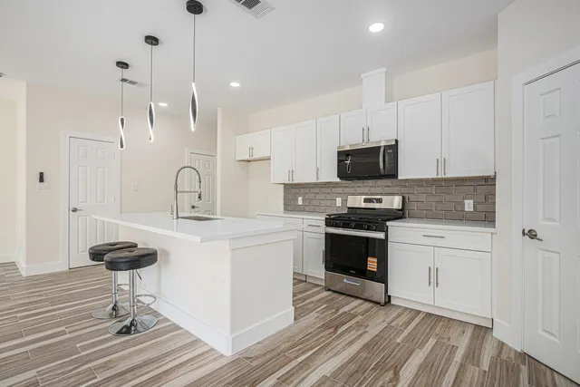 a kitchen with granite countertop a stove a sink and a refrigerator