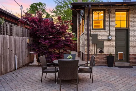 a patio with table and chairs and potted plants