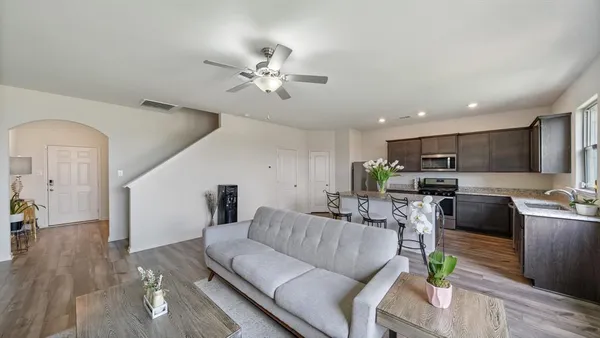 a living room with furniture kitchen view and a wooden floor