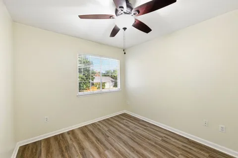 an empty room with a window and ceiling fan
