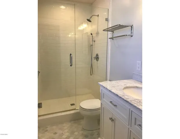 a bathroom with a granite countertop sink a toilet and shower