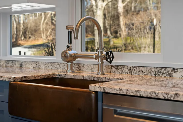 a kitchen with stainless steel appliances granite countertop a sink and a large window