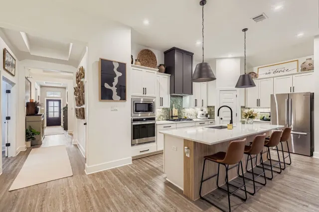 a kitchen with stainless steel appliances granite countertop a sink a stove a refrigerator and island with wooden floor