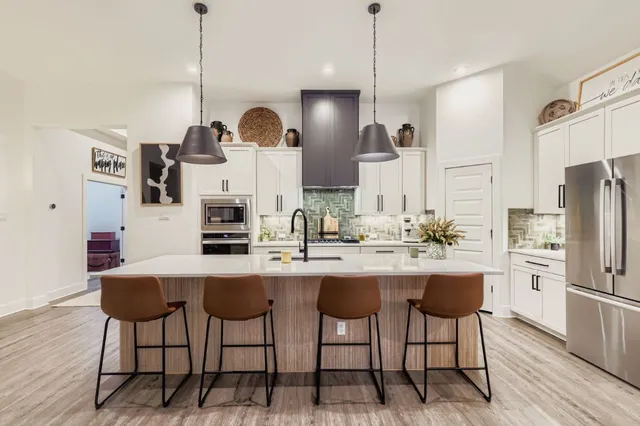 a kitchen with stainless steel appliances a dining table chairs sink and wooden floor