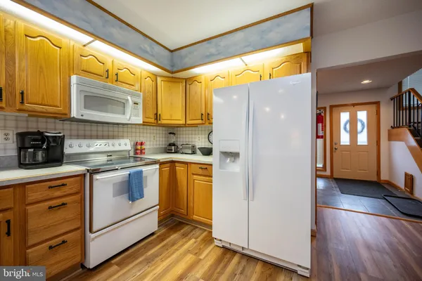 a kitchen with stainless steel appliances granite countertop a refrigerator a sink and white cabinets