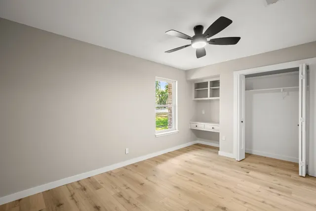 a view of empty room with wooden floor and ceiling fan