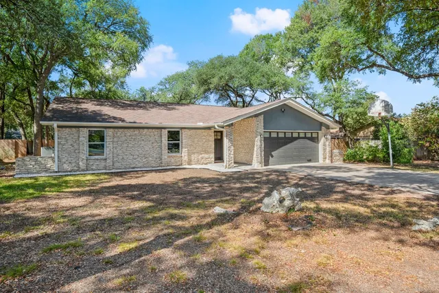 a view of a house with a yard and large tree