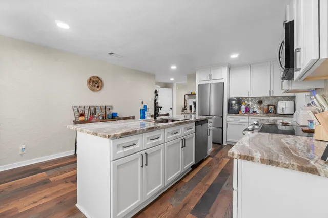 a kitchen with granite countertop a sink stainless steel appliances and cabinets