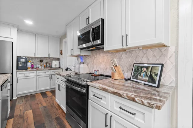 a kitchen with stainless steel appliances granite countertop a stove a sink and a microwave