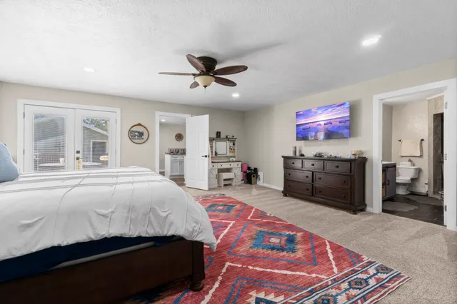 a spacious bedroom with a bed a dresser and potted plant