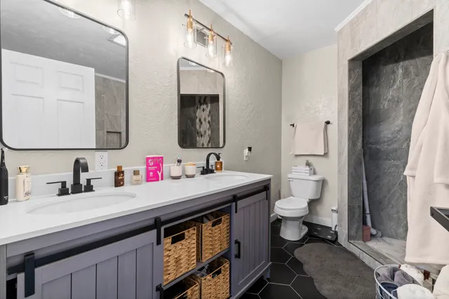 a bathroom with a sink toilet a mirror and shower