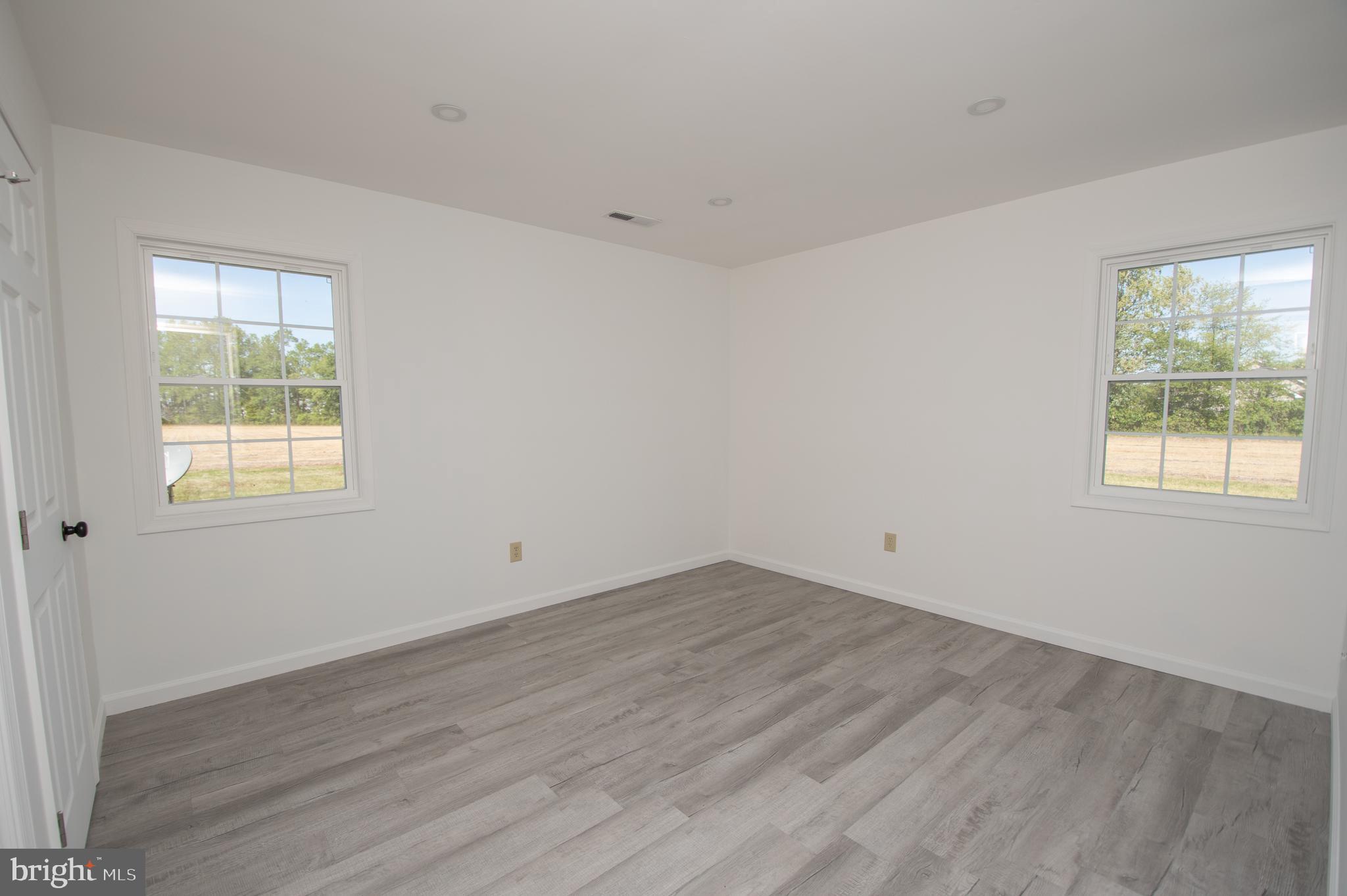 8707 Bacons Road Laurel, DE 19956 - Photo 12 of 18 an empty room with wooden floor and windows