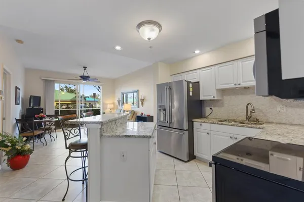a kitchen with kitchen island granite countertop a sink a stove a refrigerator and cabinets