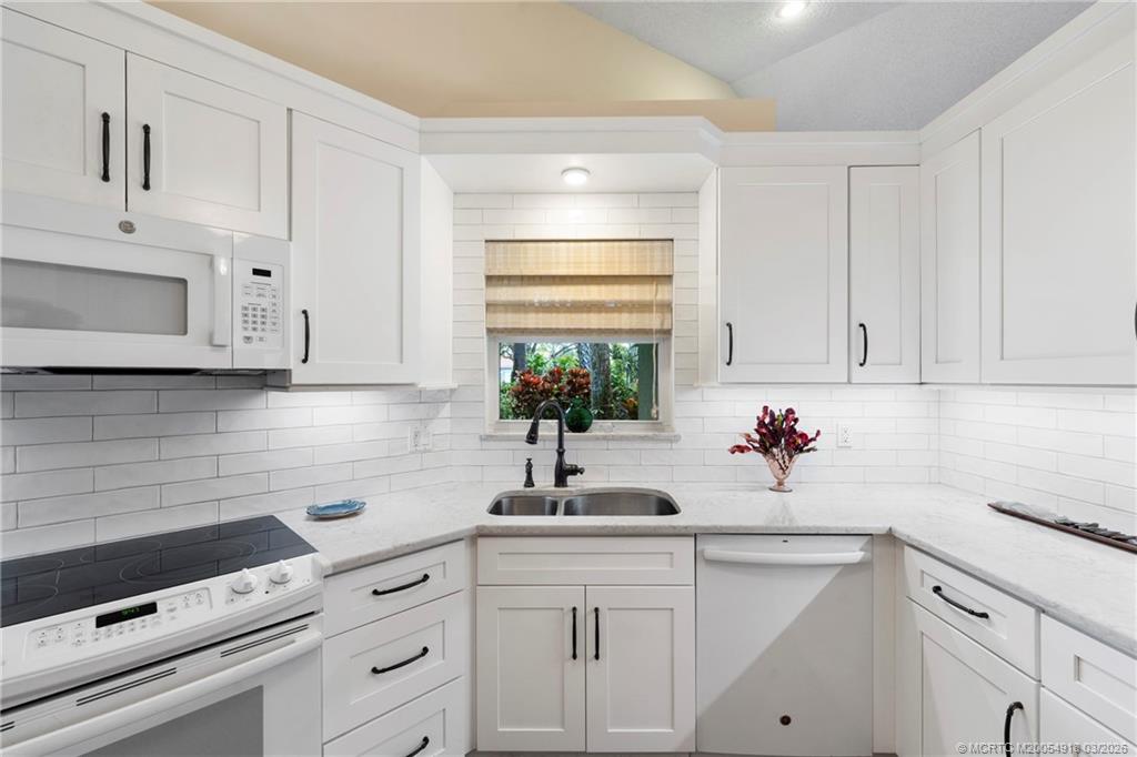 2437 Southwest Foxpoint Trail Palm City, FL 34990 - Photo 14 of 60 a kitchen with white cabinets a sink and dishwasher next to a window