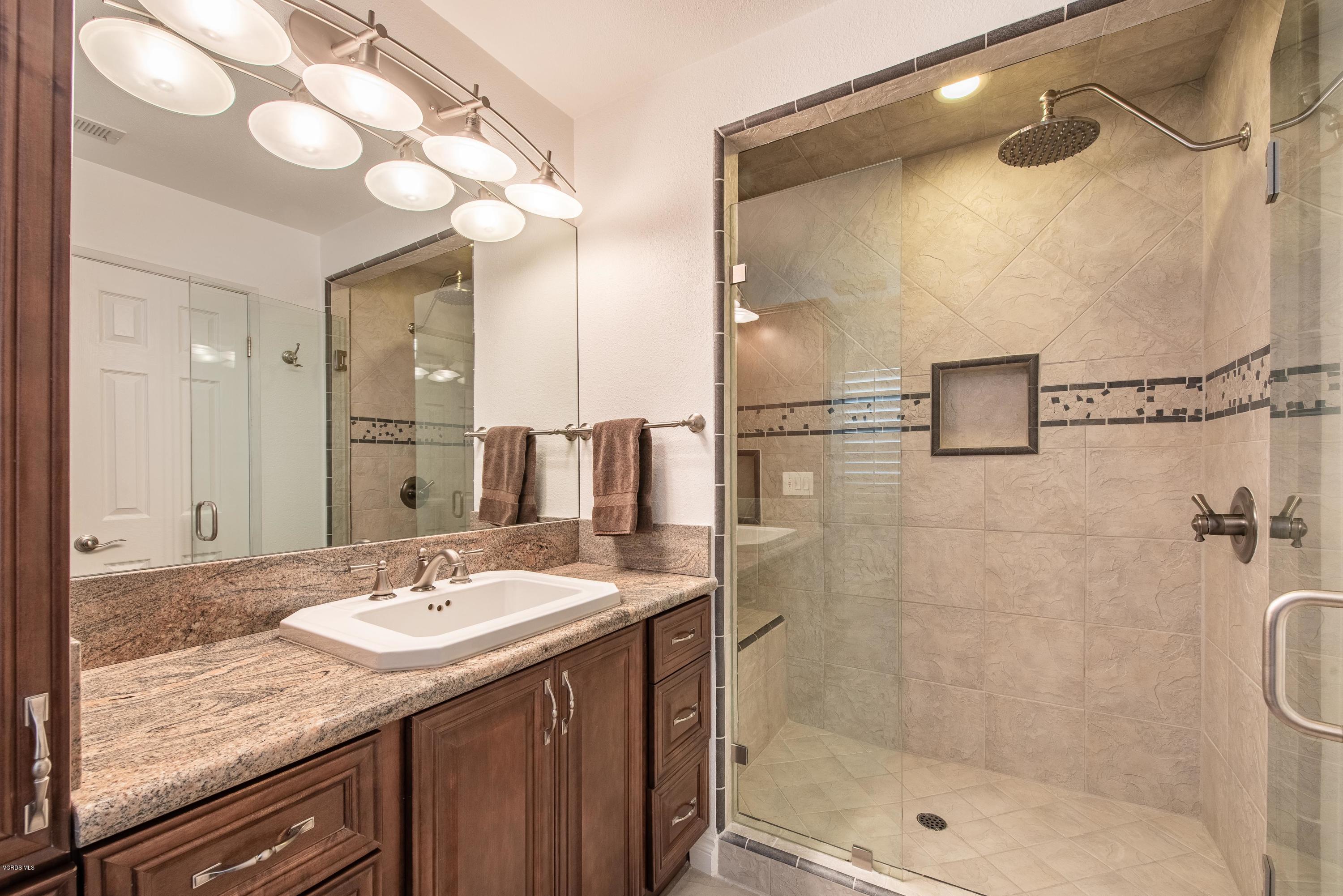 15430 Kernvale Avenue Moorpark, CA 93021 - Photo 10 of 16 a bathroom with a granite countertop sink a shower and a mirror